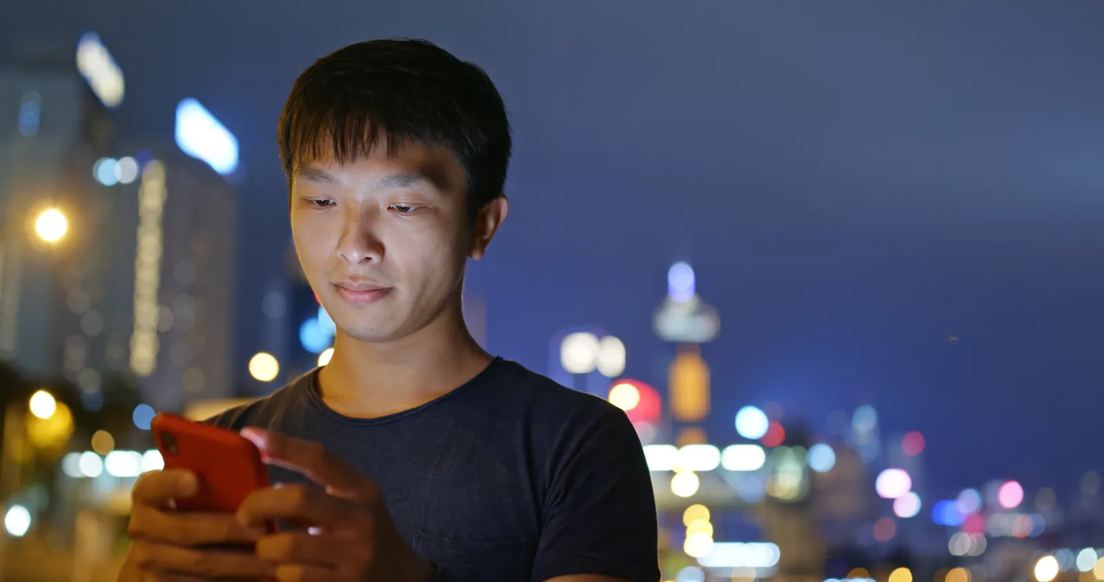 Borrower checking a repayment on his phone at night in the city