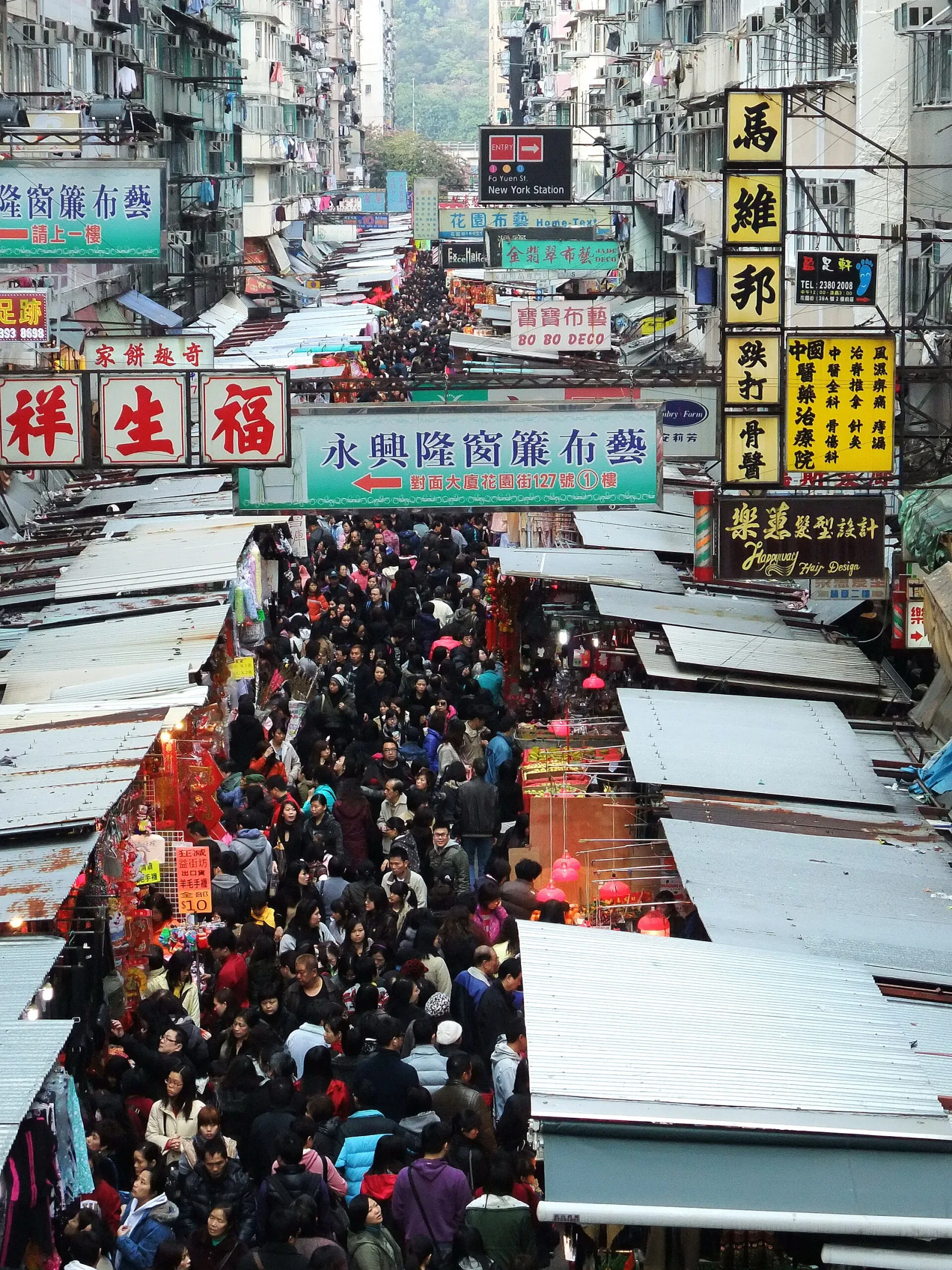 Shopfront signs above a busy street market in Mong Kok, Hong Kong